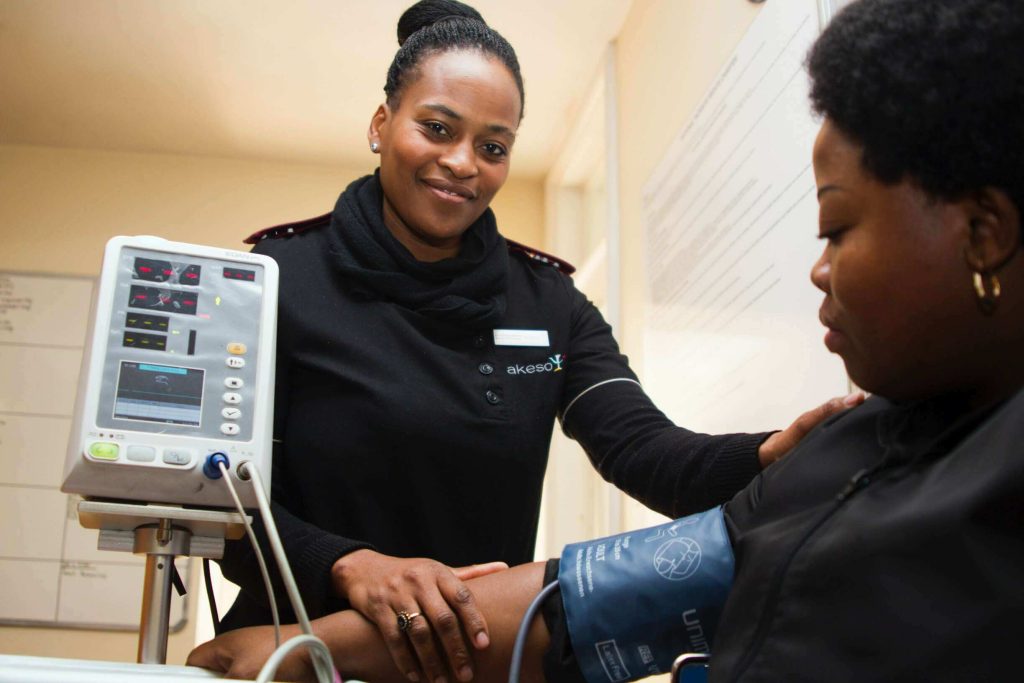 health care worker confident in her cybersecurity training uses a medical device to assist patient