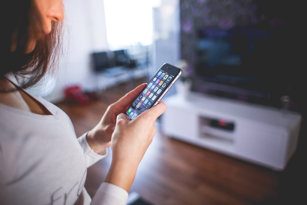 woman scrolls on her phone, ensuring her apps are updated to protect from cyberattacks