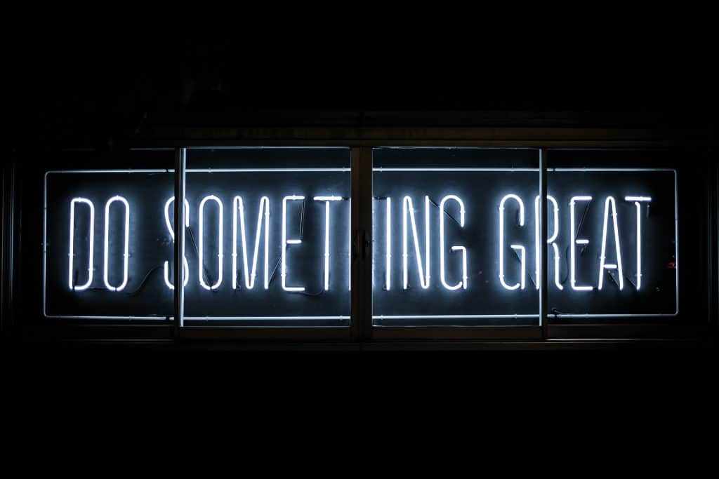 Image of a sign lit up with the words “do something great.”
